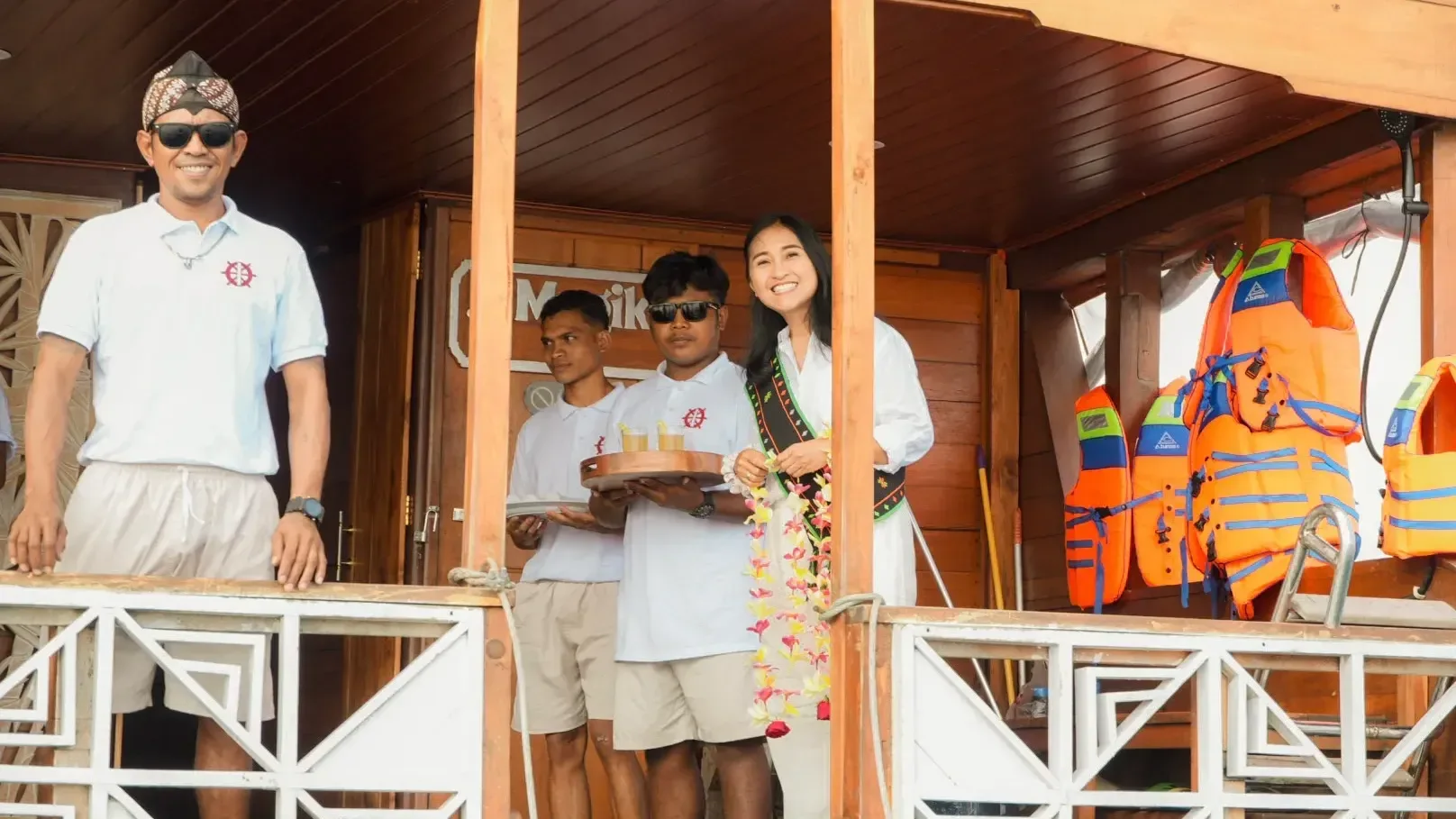 Magika crew welcoming guests aboard with drinks, life jackets stowed on the rail behind
