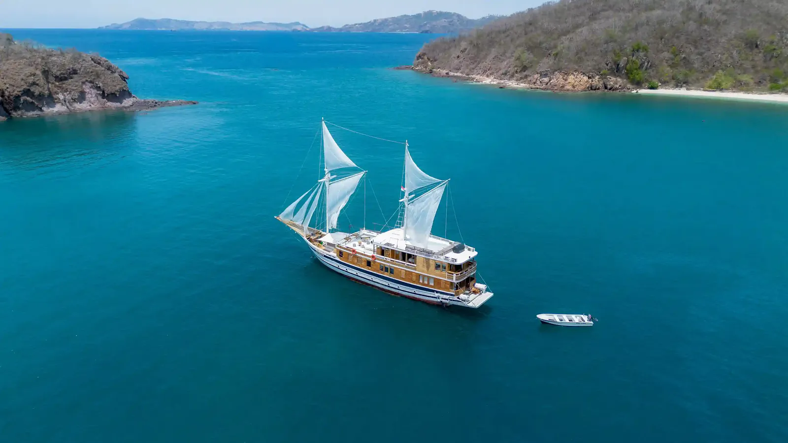 Phinisi liveaboard at anchor in Komodo National Park, seen from the air