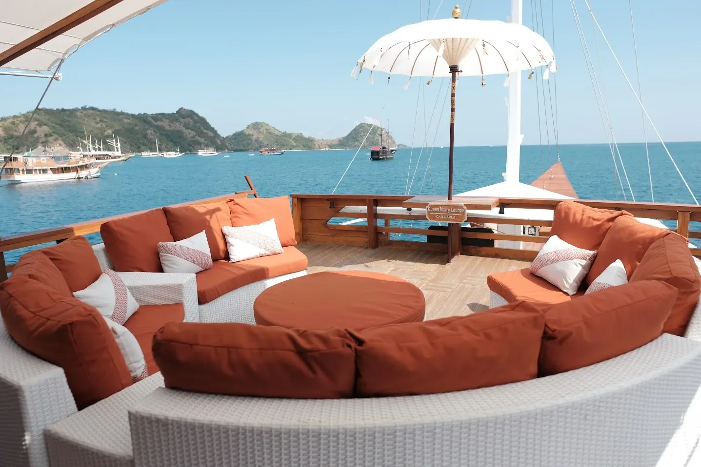 Upper-deck lounge seating under a parasol on a Komodo liveaboard